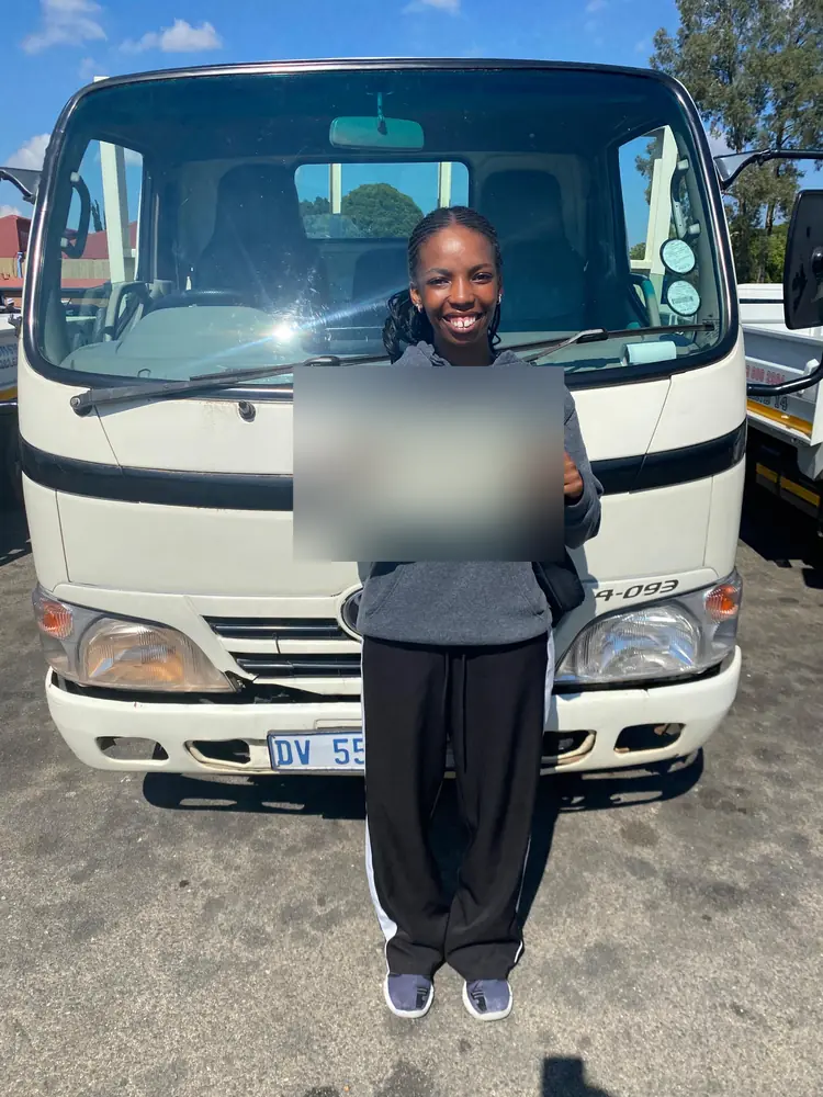Learner celebrating after passing, beside the training truck