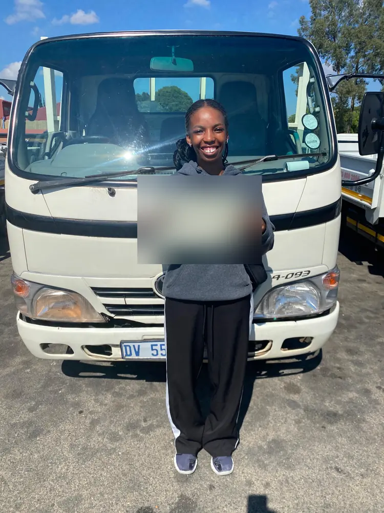 Learner celebrating after passing, beside the training truck