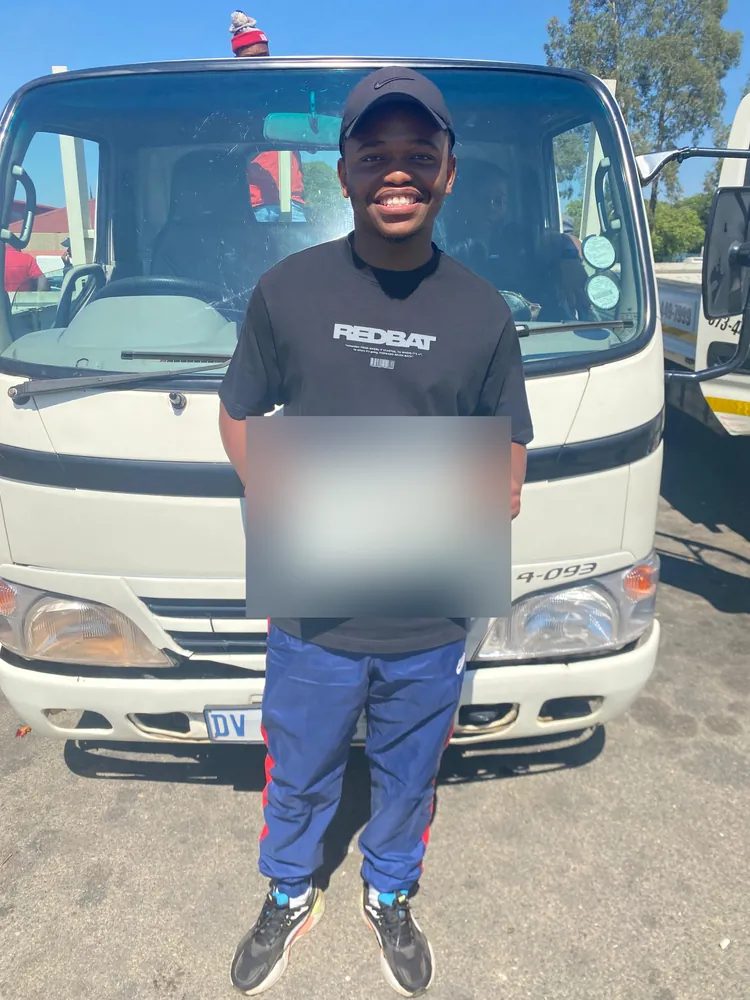 Learner celebrating after passing, beside the training truck