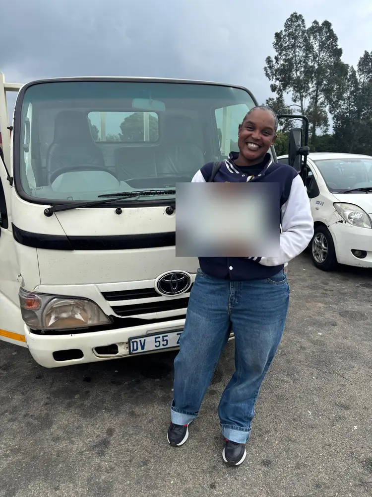 Learner celebrating after passing, beside the training truck