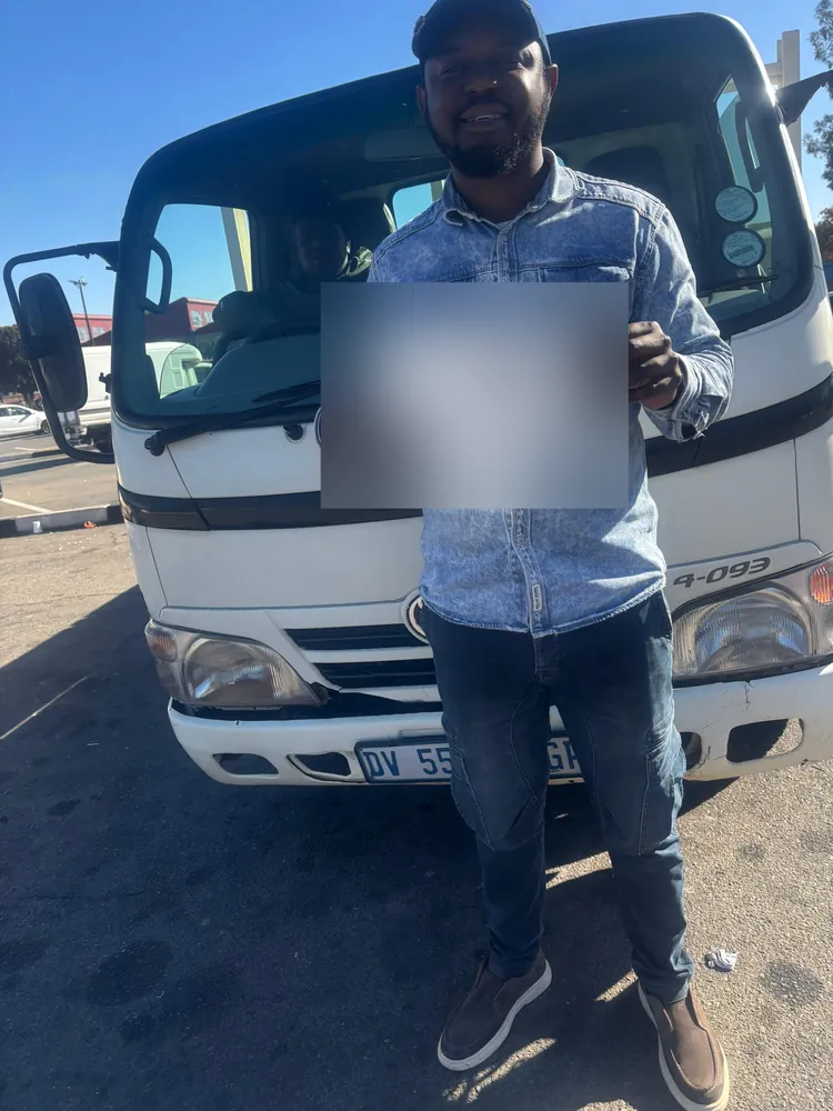 Learner celebrating after passing, beside the training truck