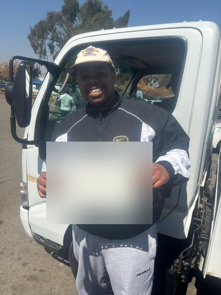 Learner celebrating after passing, beside the training truck
