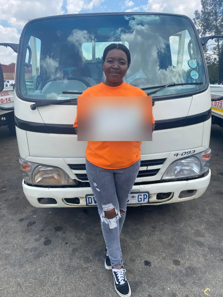 Learner celebrating after passing, beside the training truck